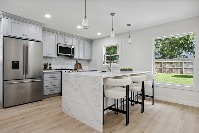 kitchen featuring recessed lighting, stainless steel appliances, gray cabinets, light wood-style floors, and tasteful backsplash
