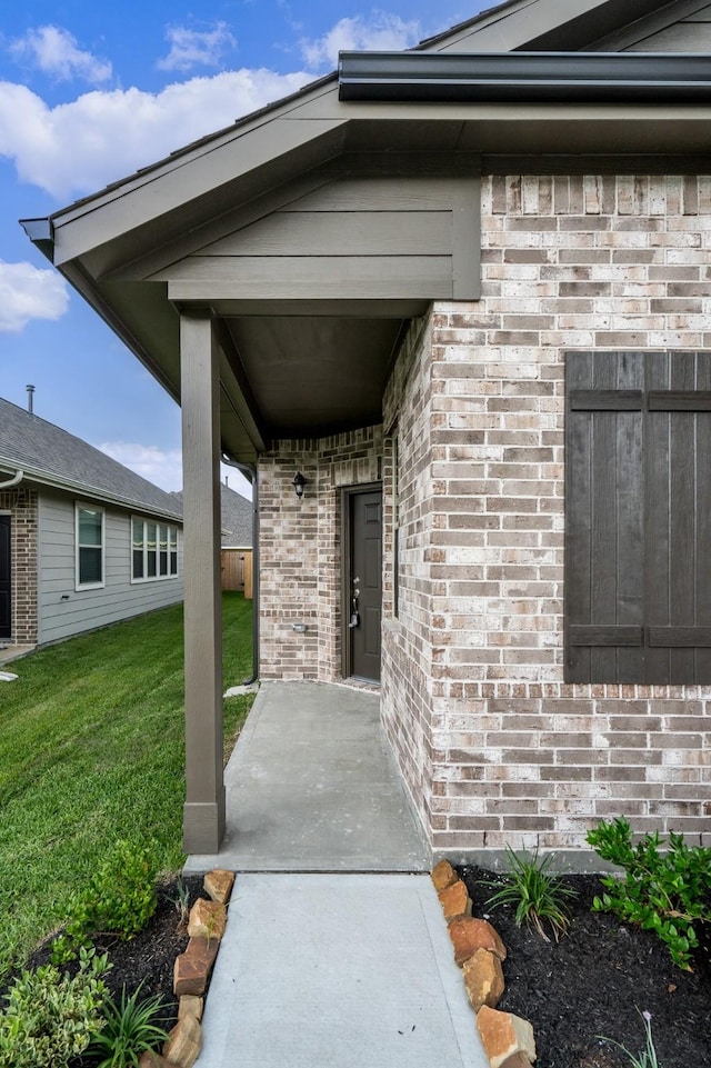 doorway to property featuring a lawn and brick siding