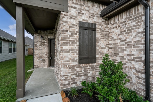 property entrance with a yard and brick siding