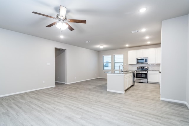 kitchen featuring visible vents, open floor plan, ceiling fan, a sink, and appliances with stainless steel finishes