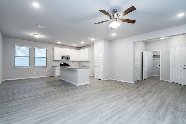 kitchen featuring baseboards, stainless steel microwave, open floor plan, and ceiling fan