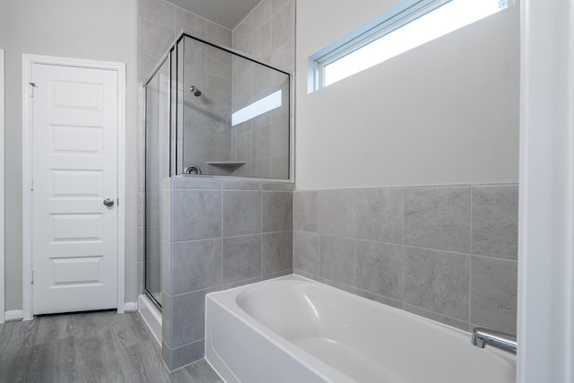 bathroom featuring a garden tub, a stall shower, and wood finished floors