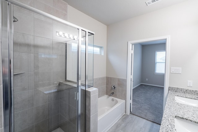 full bathroom with visible vents, wood finished floors, a bath, a sink, and a stall shower
