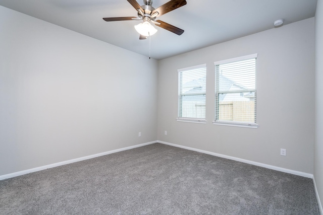 carpeted spare room featuring baseboards and a ceiling fan