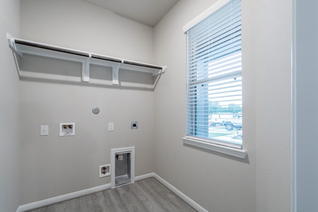 clothes washing area featuring laundry area, light wood-style flooring, baseboards, electric dryer hookup, and hookup for a gas dryer