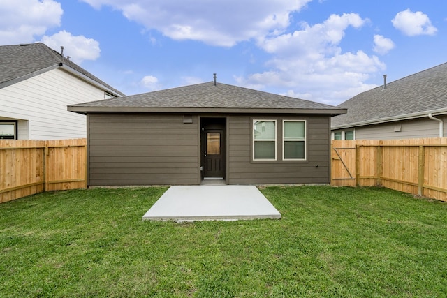 rear view of property with a fenced backyard, a shingled roof, a yard, and a patio area