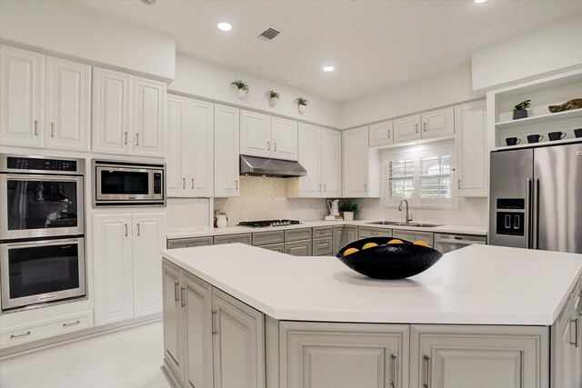 kitchen with a center island, a sink, appliances with stainless steel finishes, under cabinet range hood, and visible vents