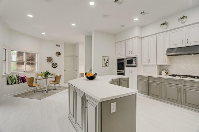 kitchen with a center island, stainless steel appliances, under cabinet range hood, visible vents, and recessed lighting