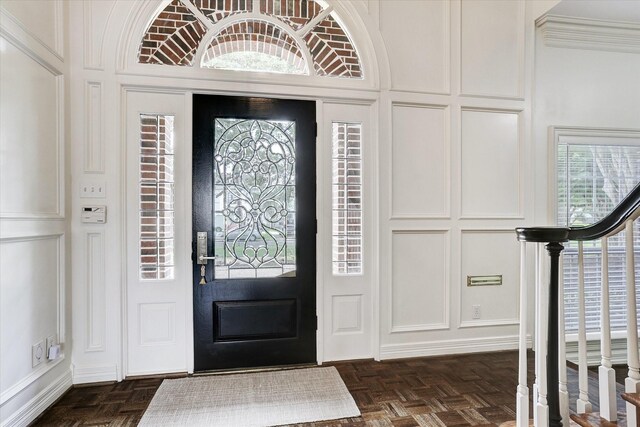 foyer entrance featuring a decorative wall, stairs, and a healthy amount of sunlight