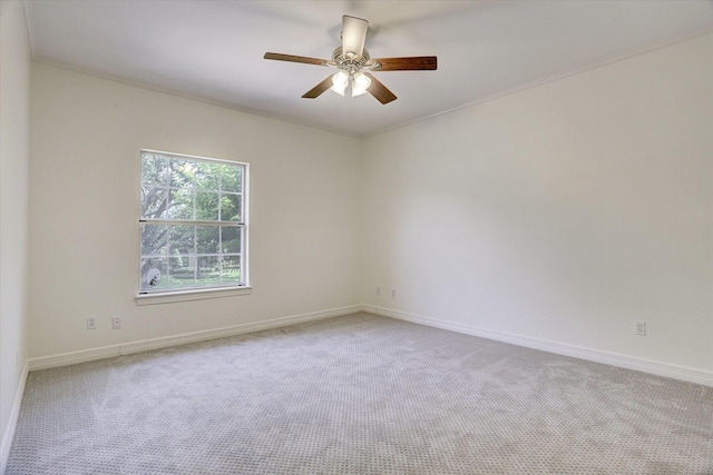 carpeted spare room featuring ceiling fan, baseboards, and ornamental molding
