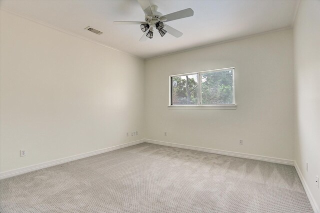 unfurnished room featuring visible vents, crown molding, baseboards, light colored carpet, and ceiling fan