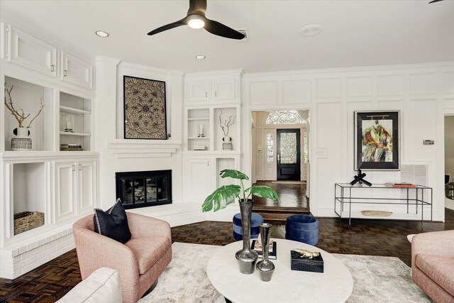 living room with a ceiling fan, built in features, a brick fireplace, visible vents, and recessed lighting
