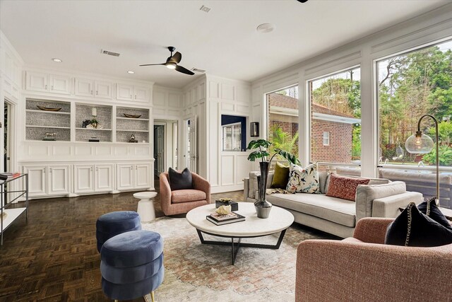 living area with a decorative wall, visible vents, a ceiling fan, and a healthy amount of sunlight