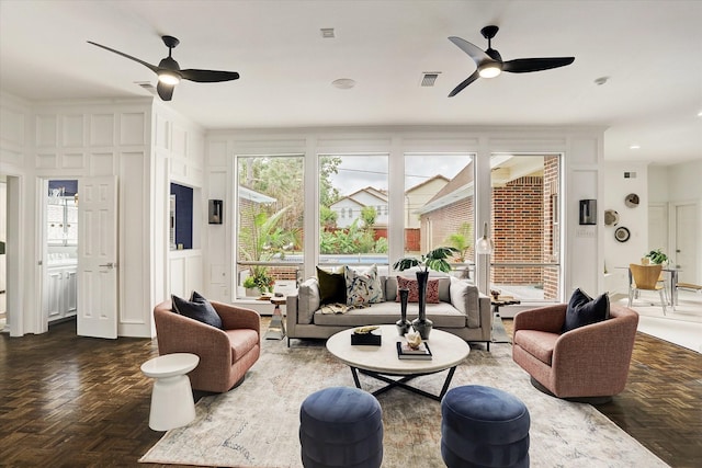 living area featuring a decorative wall, visible vents, and ceiling fan