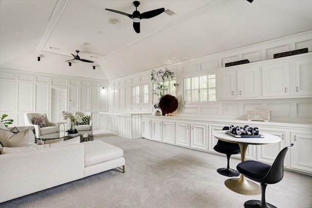 living area with a decorative wall, vaulted ceiling, ceiling fan, light carpet, and visible vents