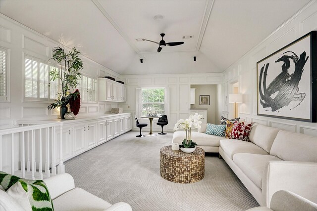 living area featuring a decorative wall, vaulted ceiling, ceiling fan, light colored carpet, and visible vents