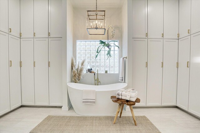 bathroom featuring wood finished floors, an inviting chandelier, and a freestanding bath
