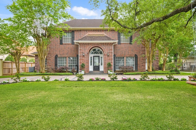 view of front of property with fence, a front lawn, brick siding, and central air condition unit