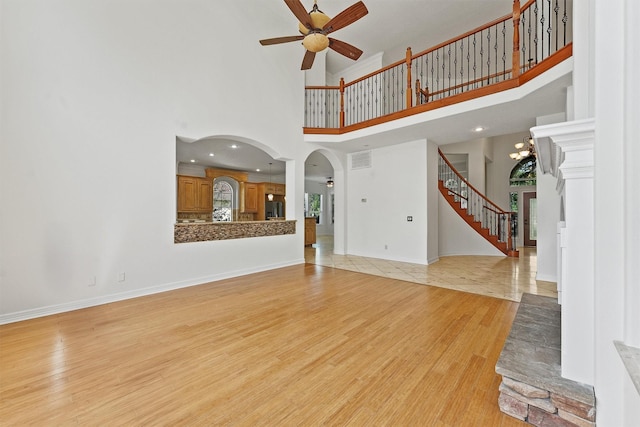 23056 Volga Dr, Porter, TX 77365 - unfurnished living room with stairway, a towering ceiling, visible vents, light wood-type flooring, and ceiling fan