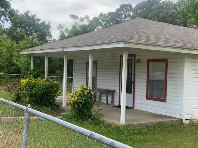 exterior space featuring fence, a porch, and roof with shingles