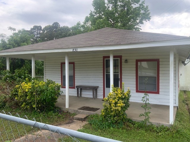 view of front of property featuring fence, a porch, and roof with shingles