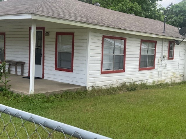 view of home's exterior featuring a lawn, a shingled roof, and a patio