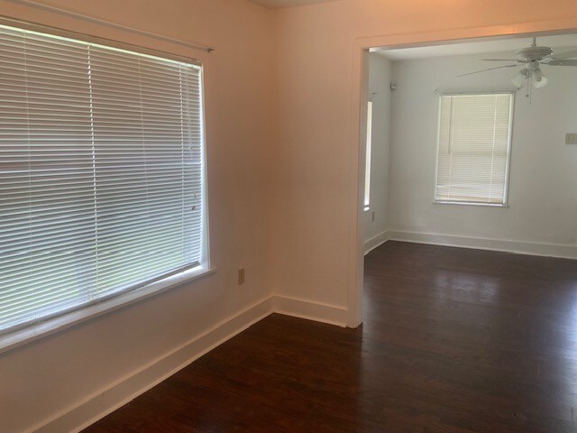 unfurnished room featuring dark wood finished floors, baseboards, and a ceiling fan