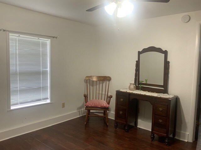 living area with ceiling fan, baseboards, and wood finished floors