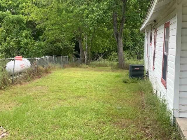 view of yard with fence and central AC unit