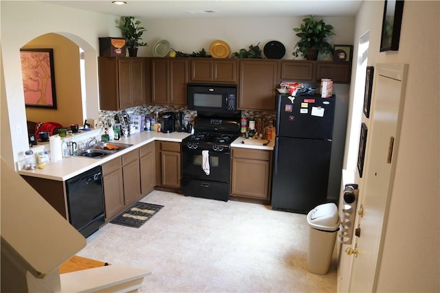kitchen featuring decorative backsplash, light countertops, a sink, and black appliances