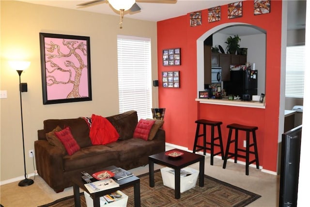 living room with arched walkways, a ceiling fan, and baseboards