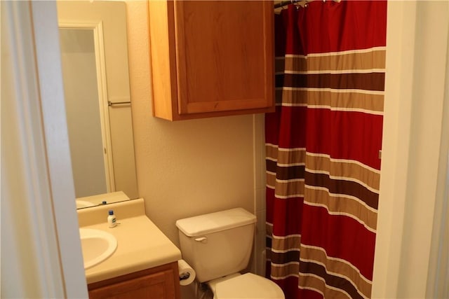 full bath with a shower with curtain, a textured wall, vanity, and toilet