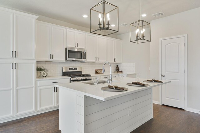 kitchen with appliances with stainless steel finishes, dark wood-style floors, a notable chandelier, and a sink