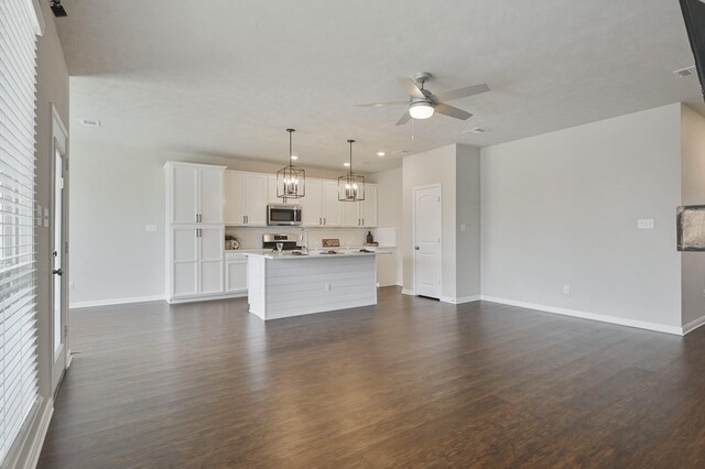 unfurnished living room with dark wood finished floors, baseboards, and ceiling fan with notable chandelier