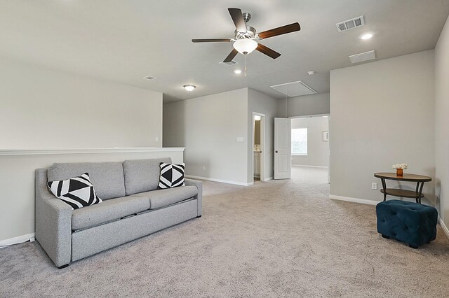 carpeted living room with attic access, visible vents, baseboards, and ceiling fan