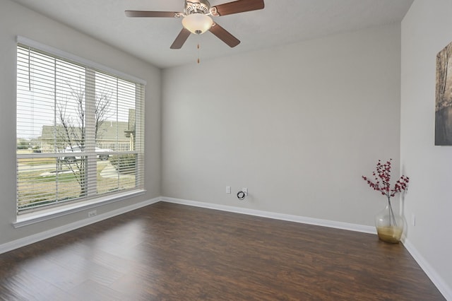 spare room with baseboards, a wealth of natural light, and dark wood-style floors