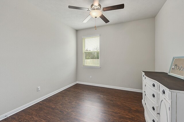 spare room with a ceiling fan, baseboards, a textured ceiling, and dark wood-type flooring