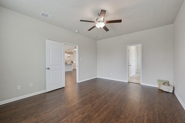 unfurnished room featuring baseboards, visible vents, ceiling fan, and dark wood finished floors