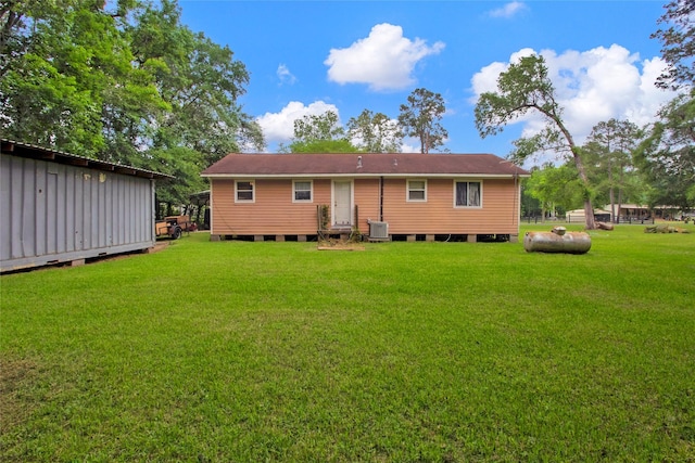 rear view of property featuring an outbuilding, a yard, and cooling unit
