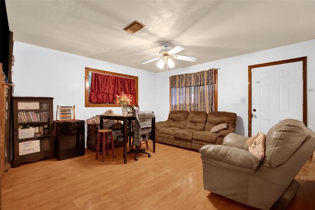 living room featuring light wood finished floors, a ceiling fan, and visible vents