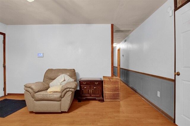 living area featuring a wainscoted wall, visible vents, and light wood-style floors