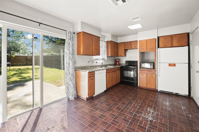 kitchen with black appliances, brick floor, a sink, and visible vents