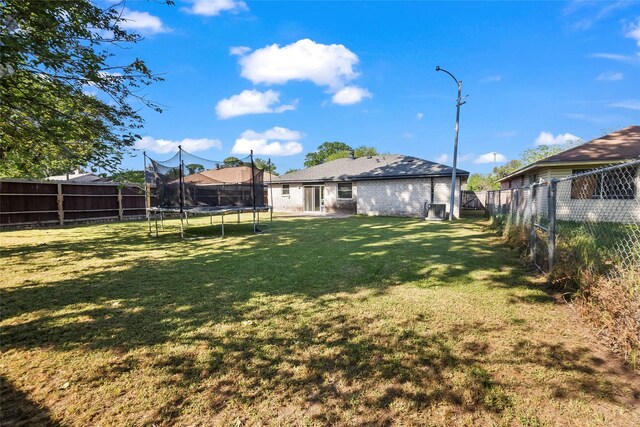 view of yard with a trampoline and a fenced backyard
