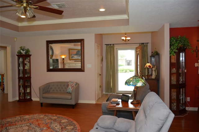 living area featuring ornamental molding, wood finished floors, visible vents, and a tray ceiling