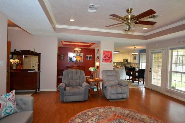 living room with wood finished floors, visible vents, and a tray ceiling