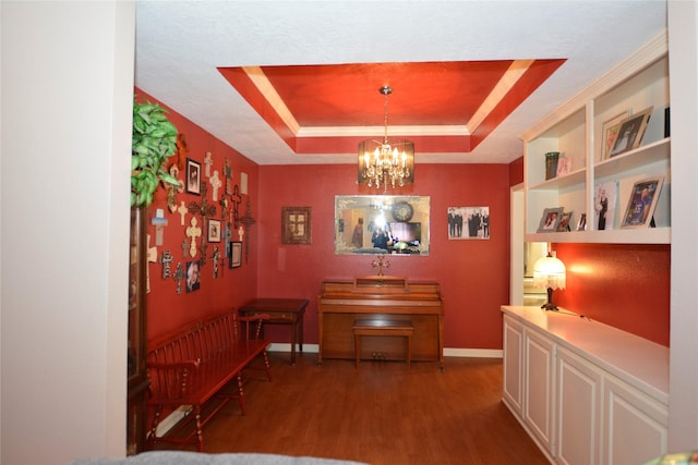 hallway with baseboards, wood finished floors, an inviting chandelier, and a raised ceiling