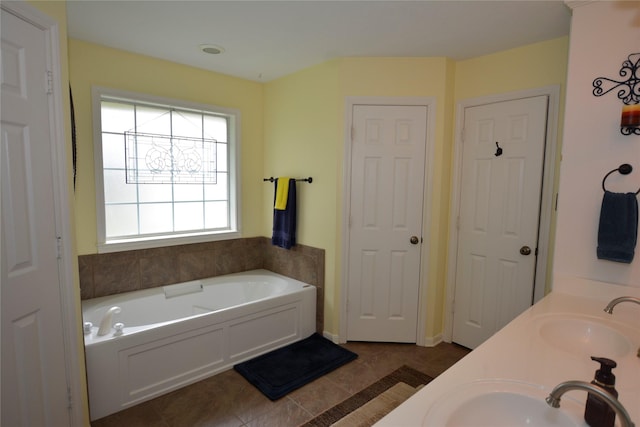 bathroom with double vanity, tile patterned floors, a bath, and a sink