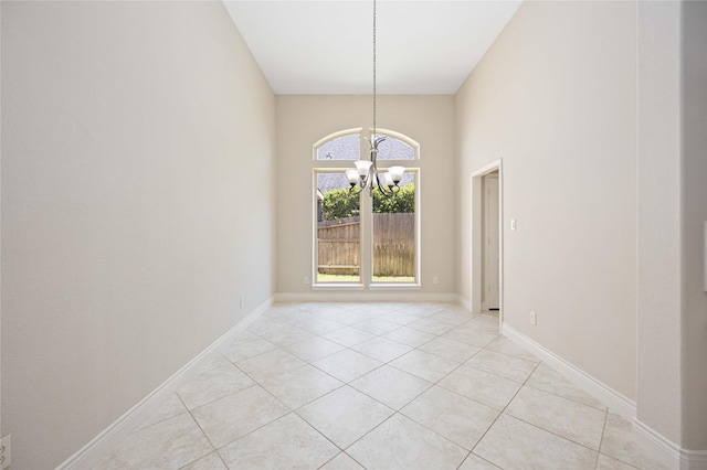 unfurnished room featuring baseboards, a notable chandelier, light tile patterned floors, and a towering ceiling