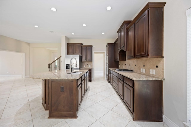 kitchen featuring gas cooktop, backsplash, stainless steel refrigerator with ice dispenser, light stone counters, and light tile patterned flooring