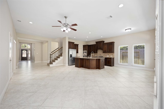 kitchen with appliances with stainless steel finishes, tasteful backsplash, light countertops, open floor plan, and light tile patterned flooring